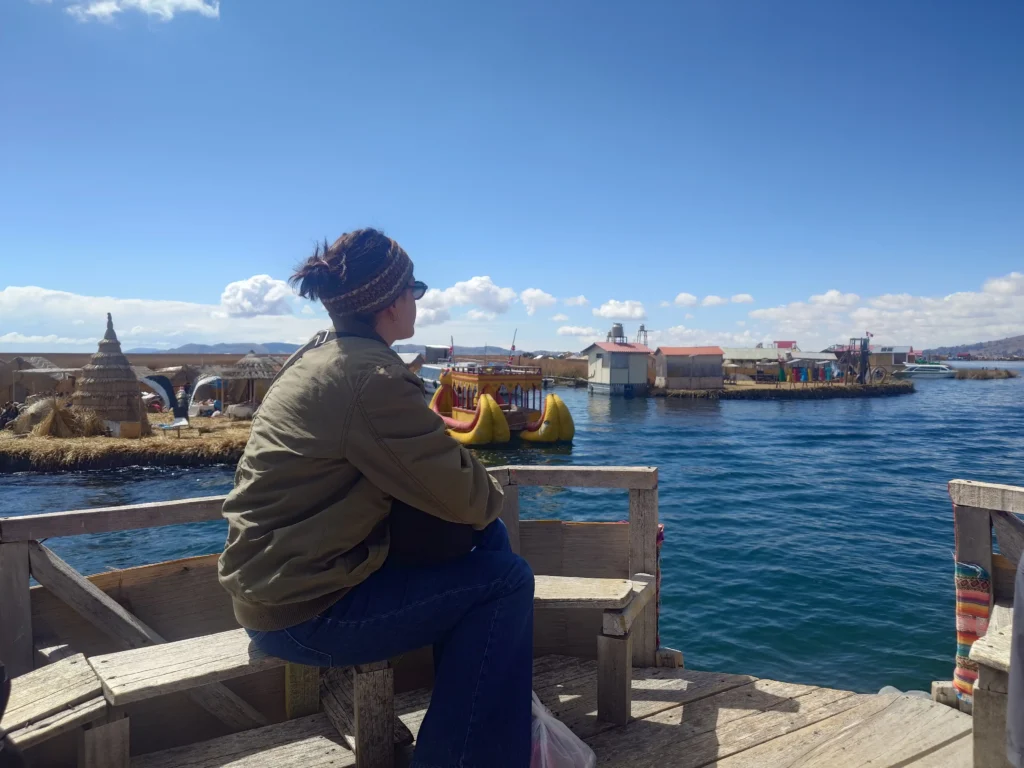 Traveler sitting by Lake Titicaca, overlooking the floating Uros Islands in Peru.